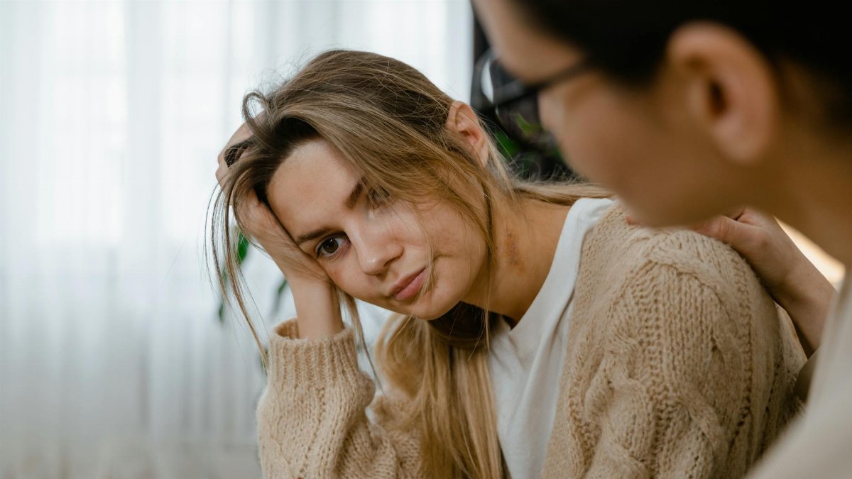 Woman receiving comforting support, showing empathy and understanding in a thoughtful indoors setting.
