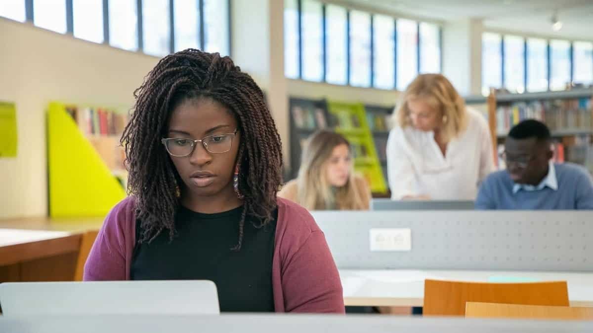Diverse group of students collaborating in a contemporary library setting, focusing on studies with a mentor.