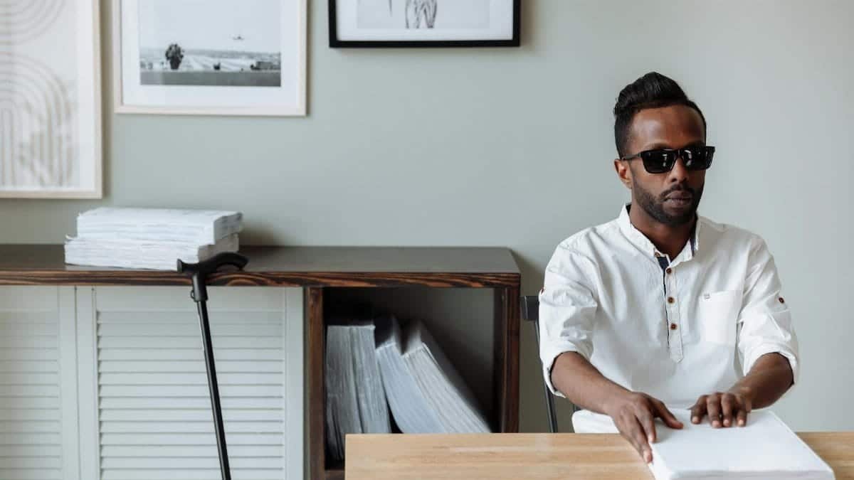 African American man reading braille indoors, showcasing independence and accessibility.