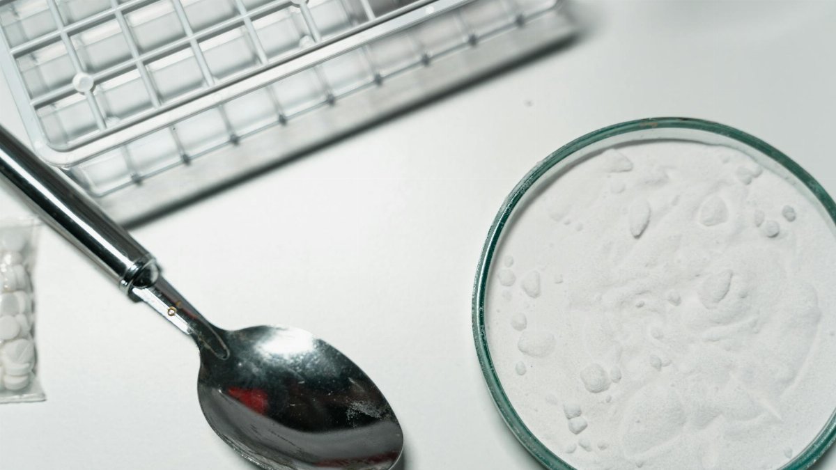 Metal spoon and white powder on a white countertop, suggesting substance use.