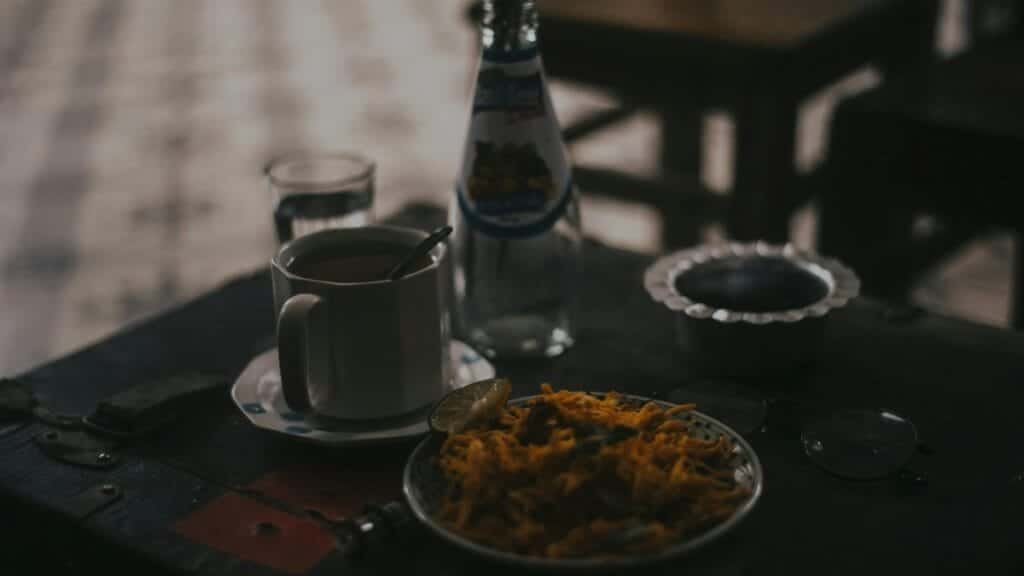 A cozy indoor scene featuring a coffee mug, bottled drink, and snacks on a table.