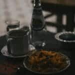 A cozy indoor scene featuring a coffee mug, bottled drink, and snacks on a table.
