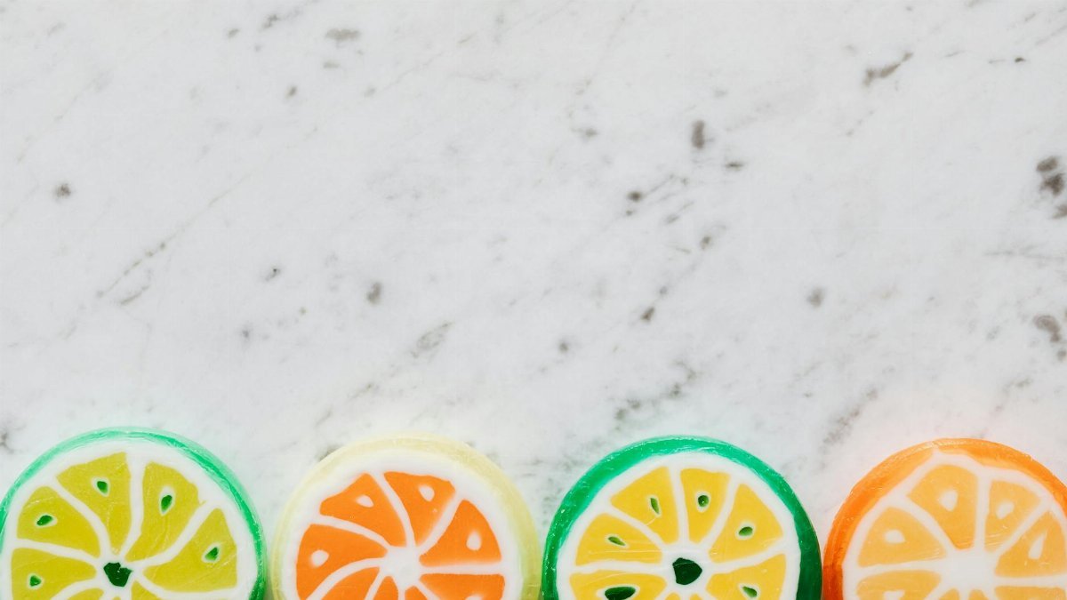 Top view of round shaped bright candies made in form of citrus fruits with wavy lines and small spots on dense surface