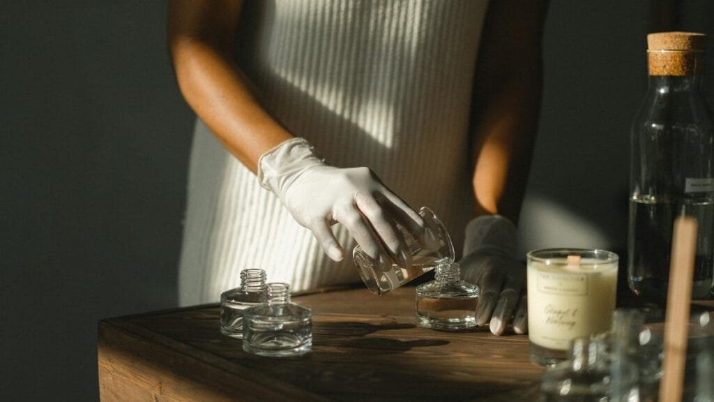Unrecognizable crop African American female pouring essential oil in glass bottle while making liquid incense at table