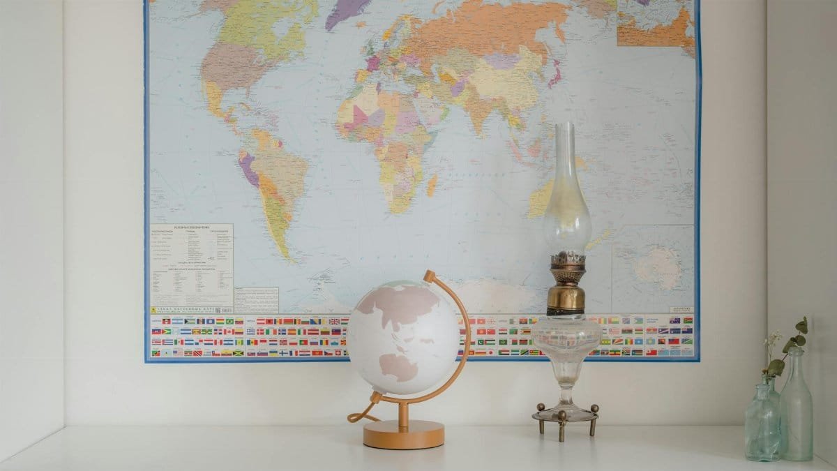 A world map displayed with a globe and vintage lamp on a shelf.