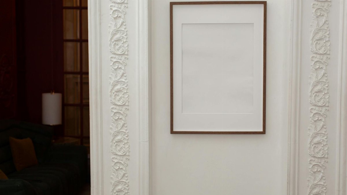 A sophisticated interior featuring a blank framed picture and a detailed ornate wall design.