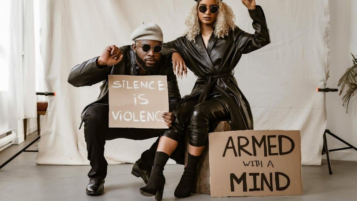 Black couple in studio with protest signs advocating peace and awareness.