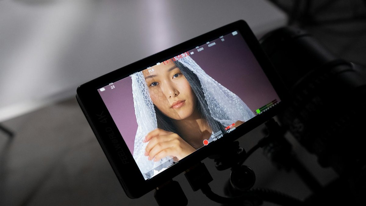 Monitor displays a studio shoot featuring a woman covered in bubble wrap, highlighting behind the scenes.