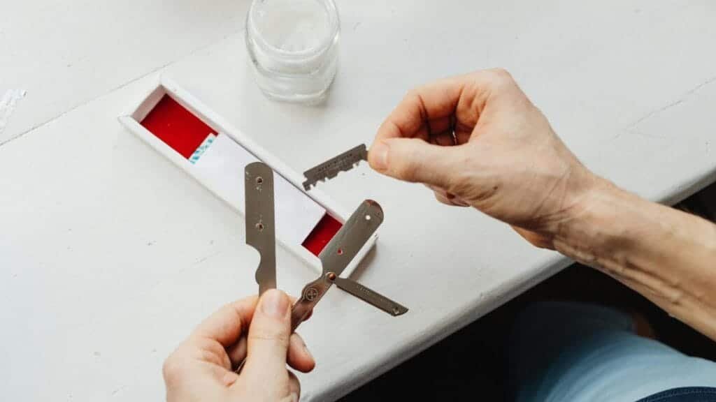 Close-up of hands assembling razor blades on a white table in natural light.