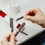 Close-up of hands assembling razor blades on a white table in natural light.