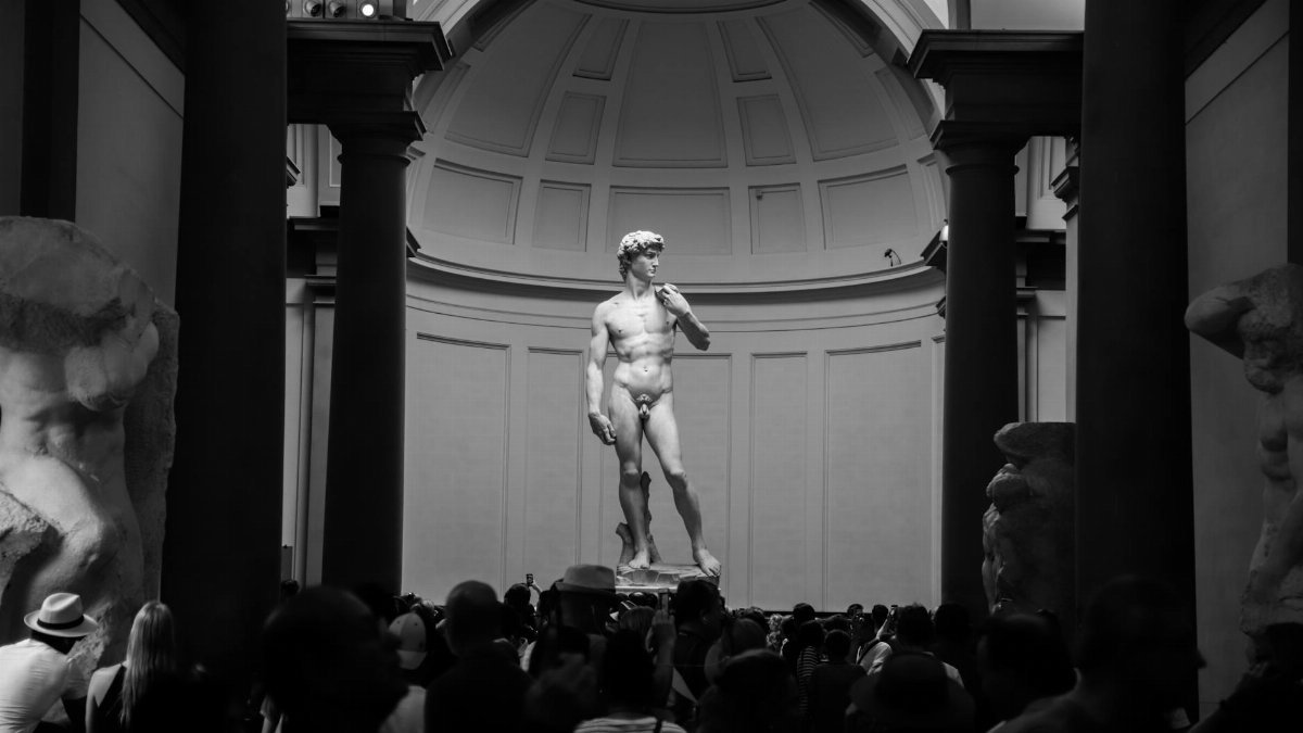 Black and white photo of Michelangelo's David statue in Florence museum.