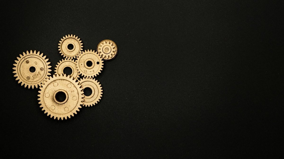 Gold gears on a black background representing industry, mechanics, and teamwork.