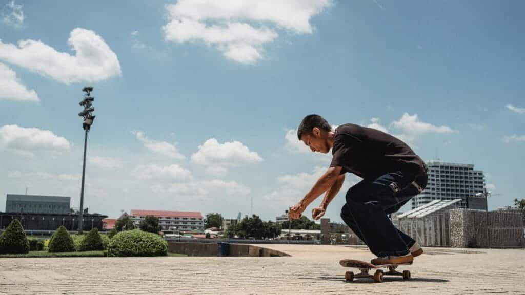 Side view of active male skater riding skateboard on sidewalk of modern city