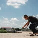 Side view of active male skater riding skateboard on sidewalk of modern city