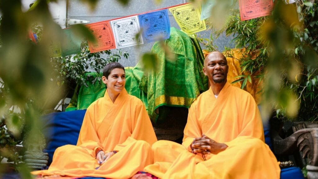 Two people in Buddhist robes enjoy a serene meditation ceremony outdoors, embracing spirituality.