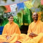 Two people in Buddhist robes enjoy a serene meditation ceremony outdoors, embracing spirituality.