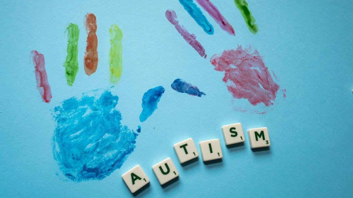 Colorful child handprints and autism text on a blue background, promoting awareness.