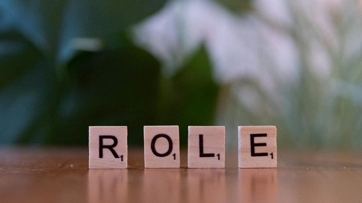 Close-up of Scrabble tiles spelling 'ROLE' on a wooden surface with a blurred background.