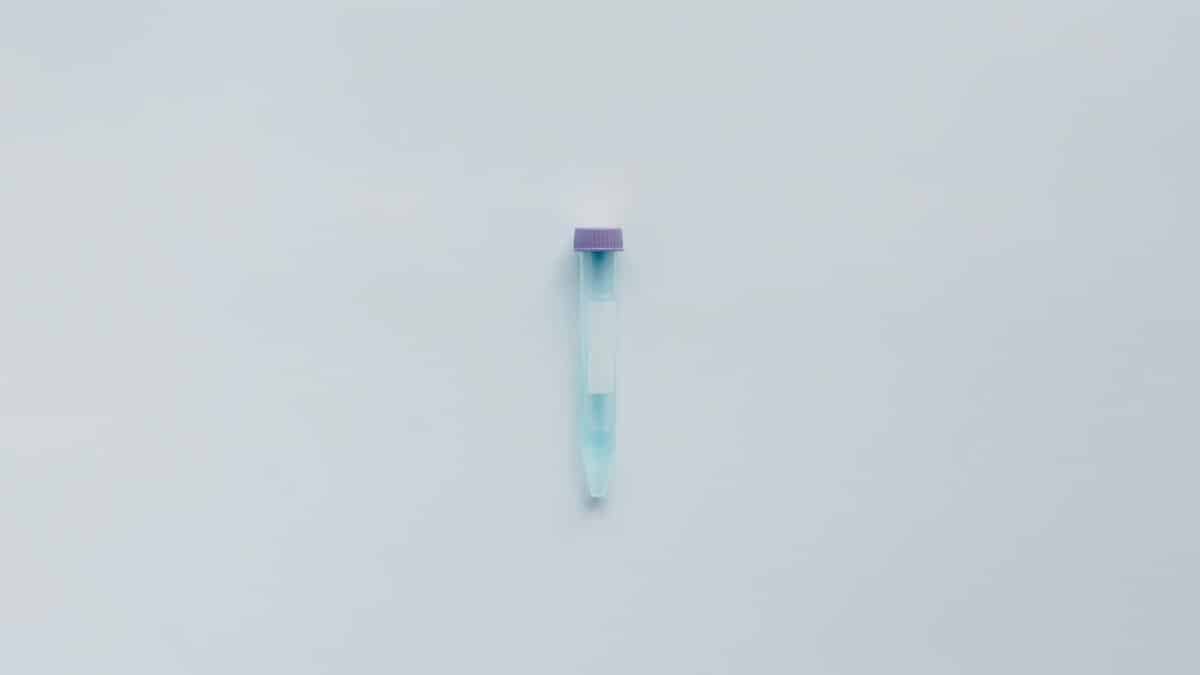 A single test tube with blue liquid and a purple cap on a white background.