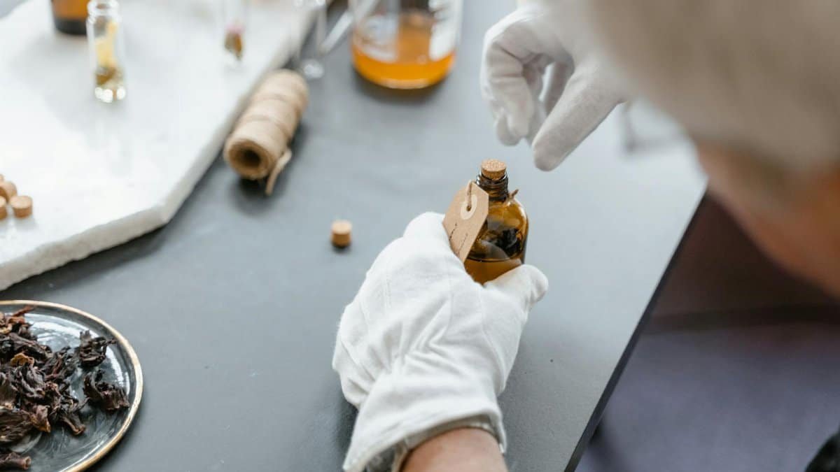 Person in gloves carefully handling aromatic compound in laboratory setting with various ingredients.