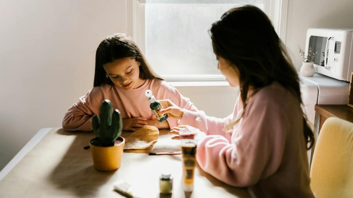 A mother and daughter enjoying a craft project together by the window.