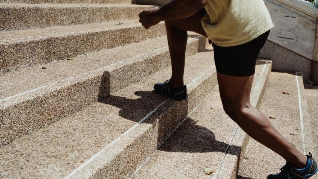 A man running up stone stairs outdoors, showcasing fitness and urban exercise.