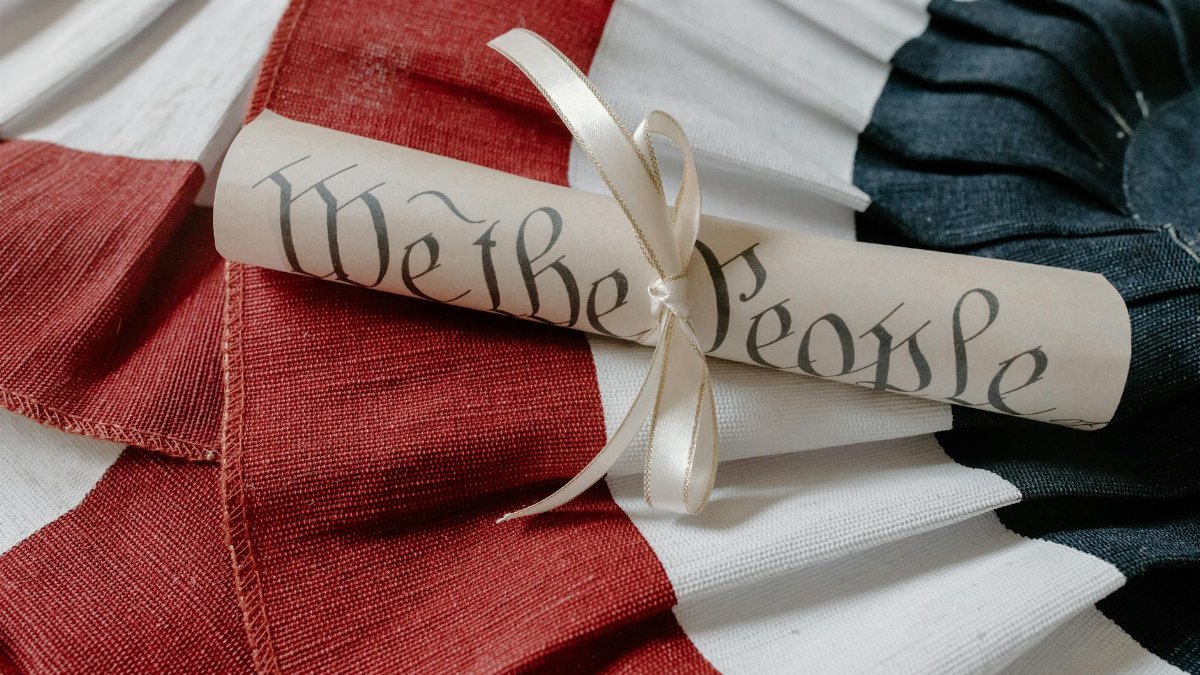 Close-up of a 'We the People' scroll on an American flag cloth background.