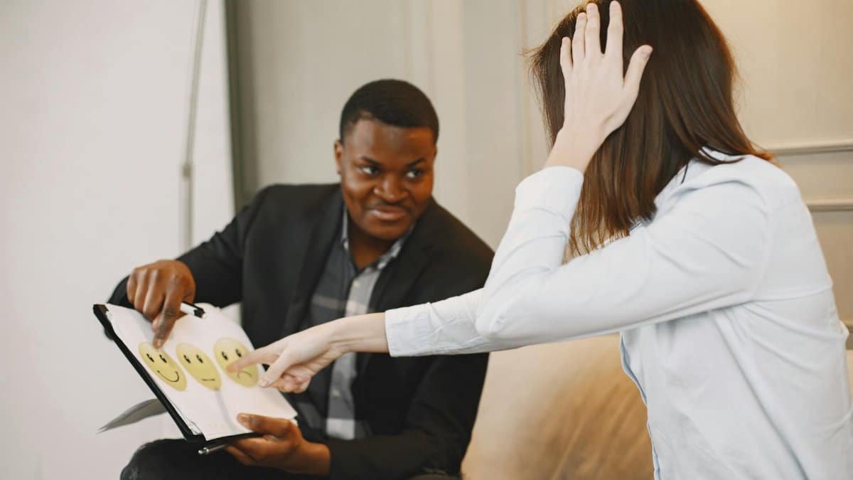 African American man and woman discussing emotions with emoji cards in a therapy session.