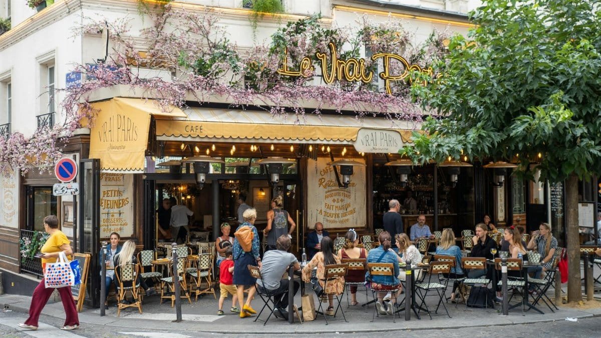 Outdoor view of Le Vrai Paris bistro in Montmartre, Paris, with people dining and vibrant atmosphere.