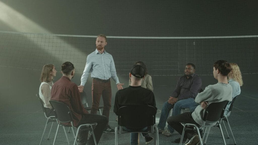 A diverse group participating in a therapy session with a facilitator indoors.