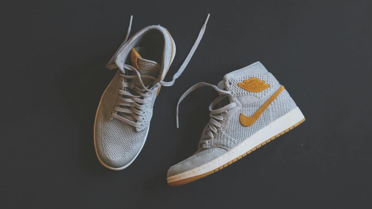 Close-up of fashionable gray and orange high-top sneakers displayed against a minimal background.