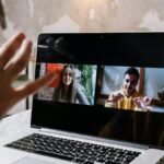 Hands gesturing during a video call on a laptop screen, showing two people in a virtual meeting.