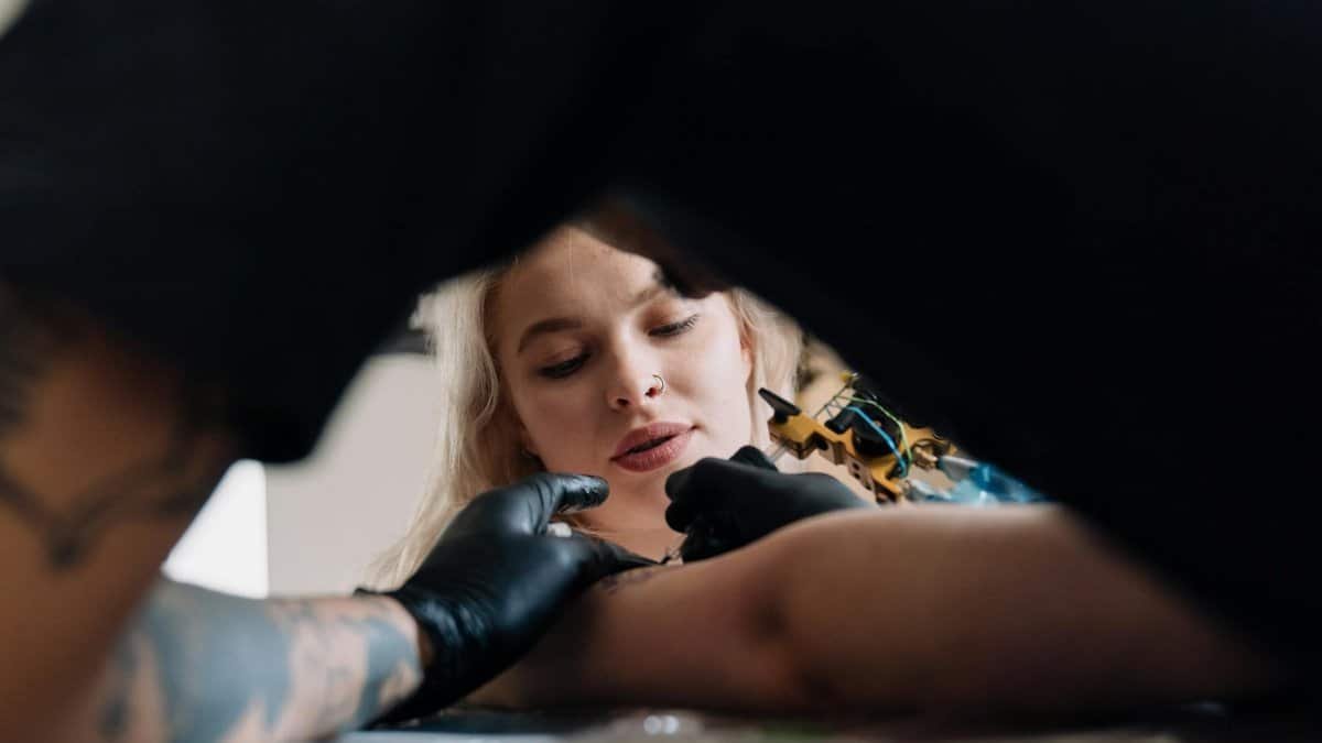 Tattoo artist working on a client's arm in a studio setting, showcasing the artistic process.