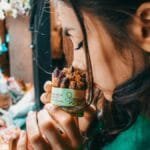 A woman savoring the scent of potpourri at a vibrant London market, capturing the essence of street life.