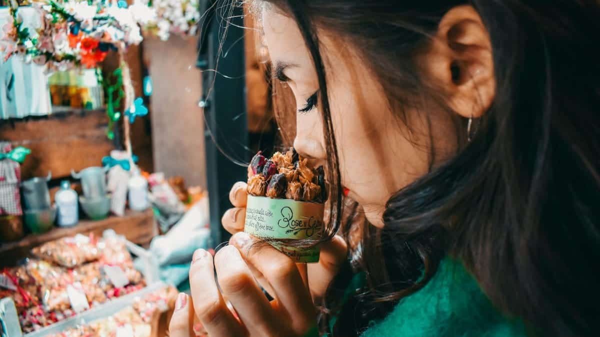 A woman savoring the scent of potpourri at a vibrant London market, capturing the essence of street life.
