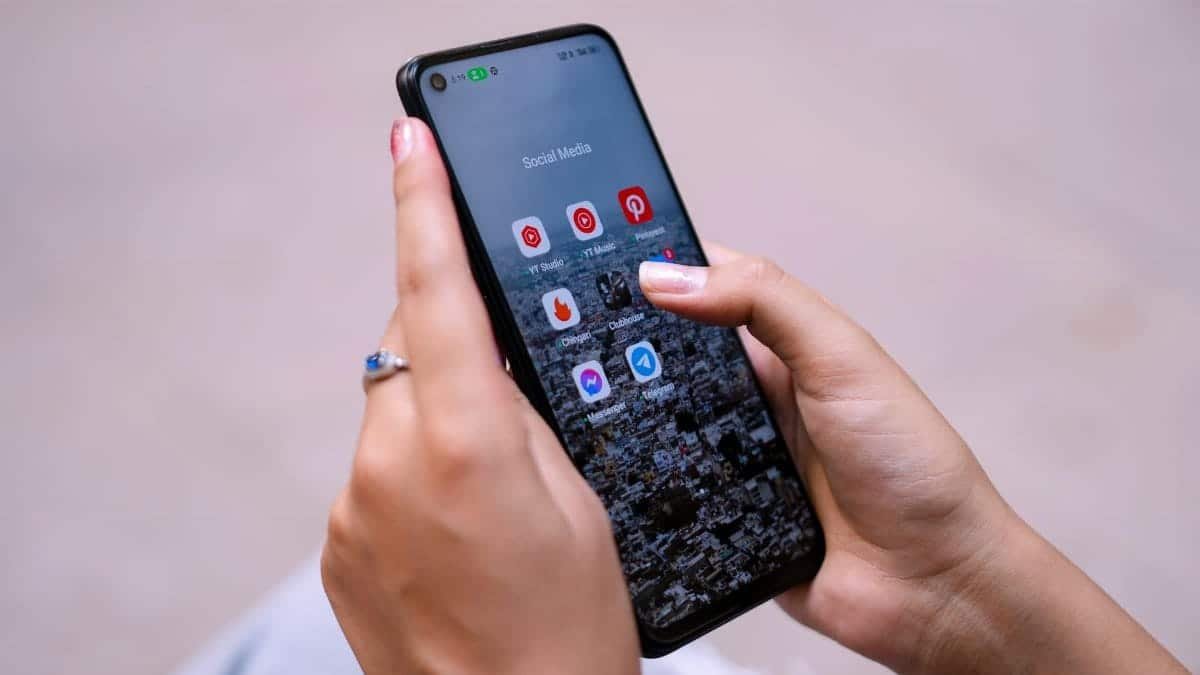 Close-up of hands holding a smartphone displaying social media apps, emphasizing digital connectivity.