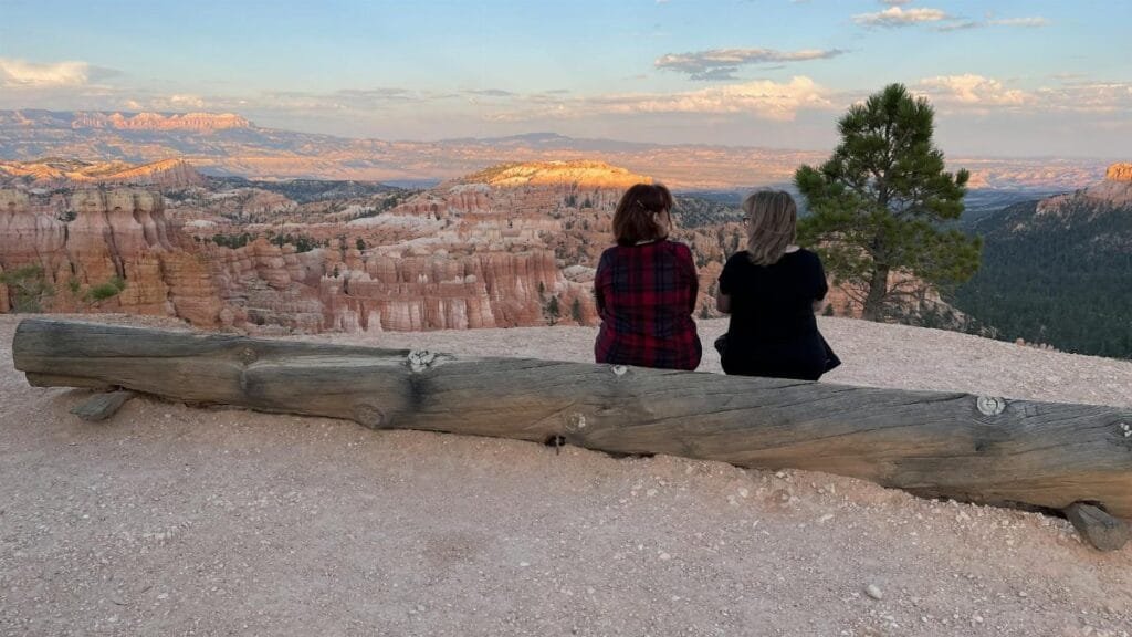 Two friends sitting and enjoying the stunning sunset view at Bryce Canyon in Utah.