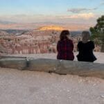 Two friends sitting and enjoying the stunning sunset view at Bryce Canyon in Utah.