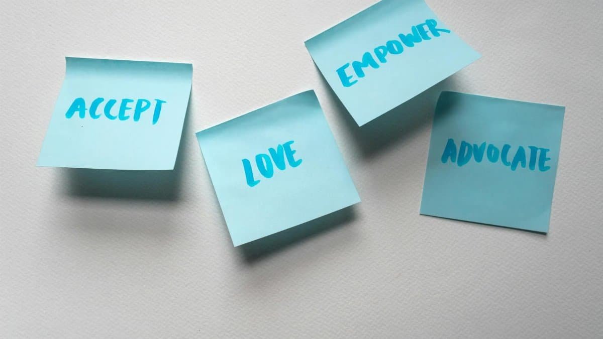 Four blue sticky notes with motivational words on a white surface.