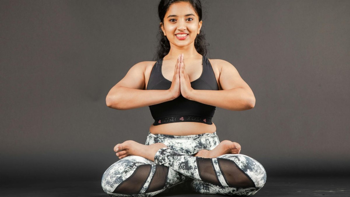 A South Asian woman in a yoga pose indoors, showcasing serenity and flexibility.