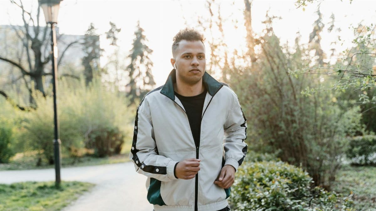 A young man jogging outdoors in a park during sunset, showcasing fitness and an active lifestyle.