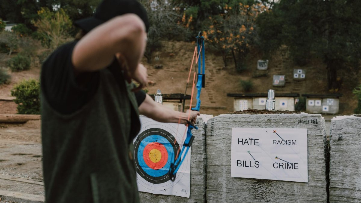 A person targets social issues with arrows symbolizing a fight against hate, racism, crime, and bills.