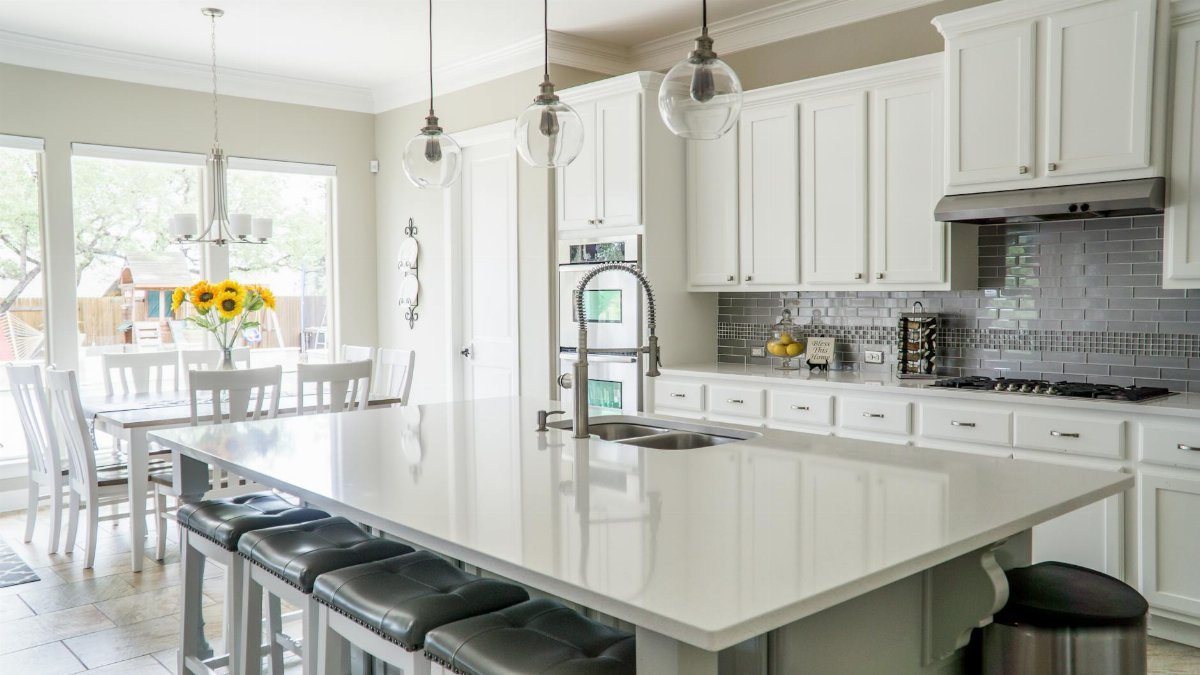Spacious modern kitchen with white cabinets and island in natural light.