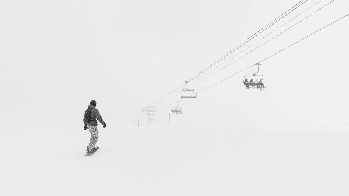 Snowboarder gliding under ski lifts in snowy Breckenridge, Colorado.