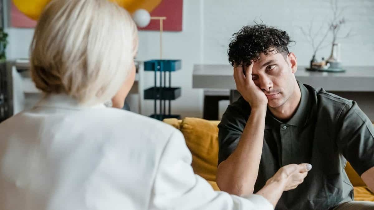 A therapist in session with a young man in a modern, artistic office setting.