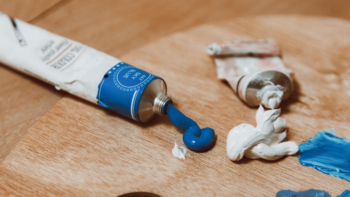 Bright blue and white paint tubes on a wooden palette, perfect for art inspiration.
