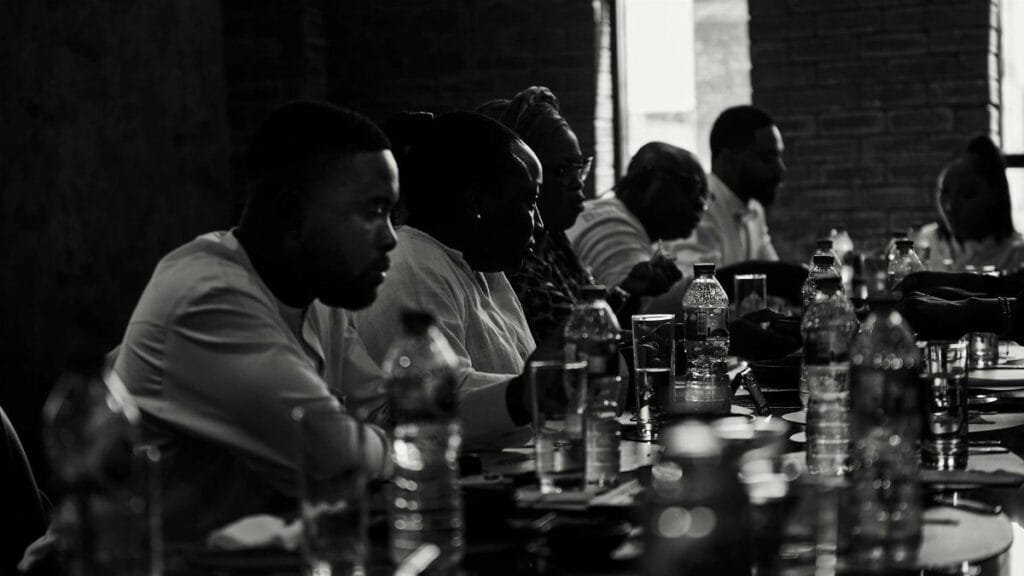 A diverse group of adults engaged in a dinner meeting, captured in black and white.