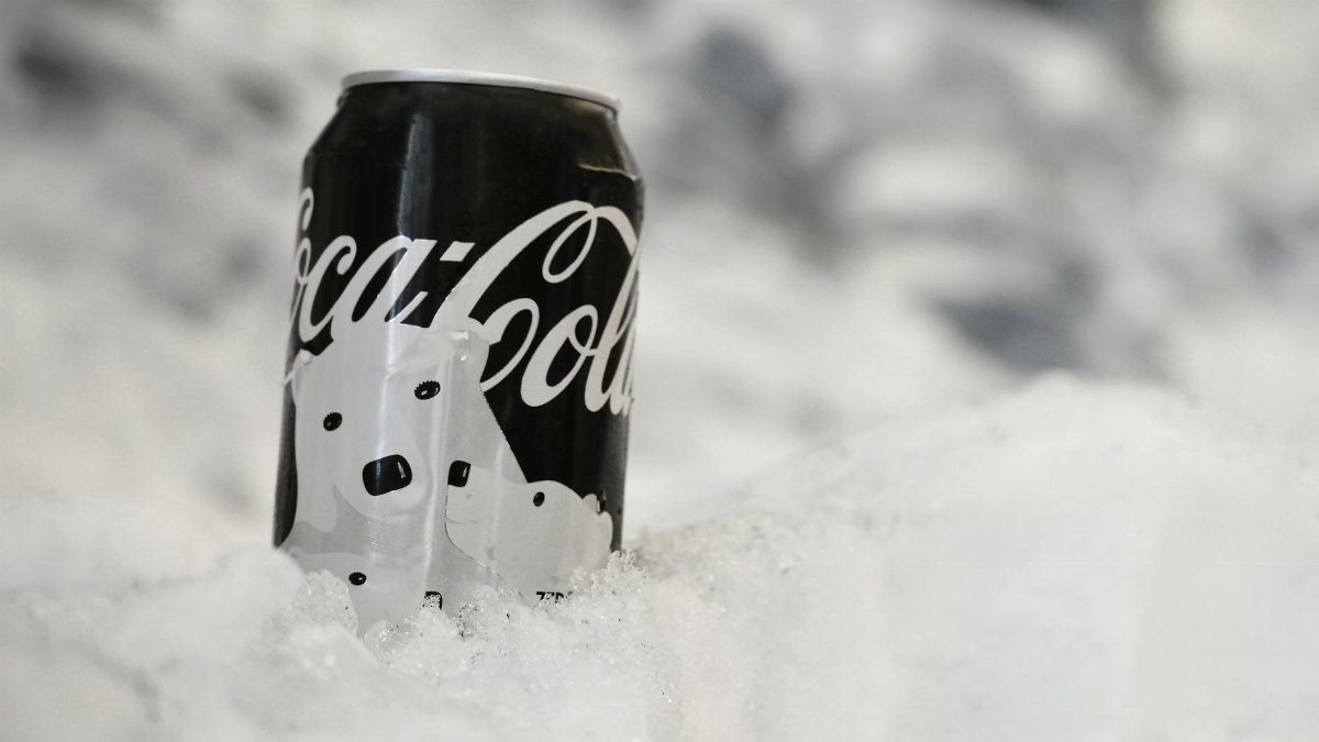 A close-up of a Coca-Cola can covered in frost and surrounded by snow, evoking a wintery and refreshing feel.