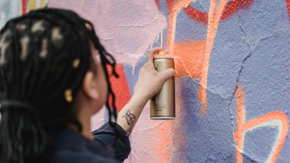 A woman spray painting vibrant street art on a wall, captured in close-up.