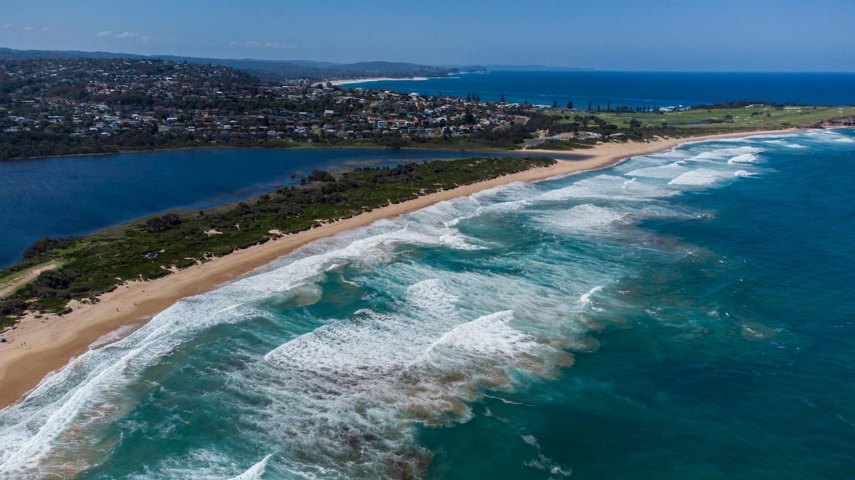 A stunning aerial shot of Dee Why Beach showcasing waves, shoreline, and lush surroundings.